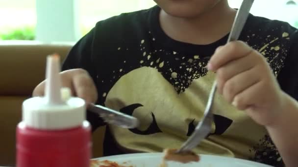 Kleiner asiatischer Junge isst Steak mit Gemüsesalat im Restaurant mit einem Lächeln im Gesicht — Stockvideo