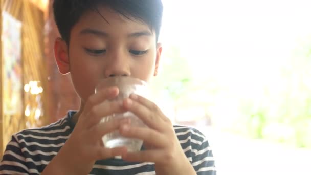 Joven niño asiático bebiendo un vaso de agua  . — Vídeo de stock