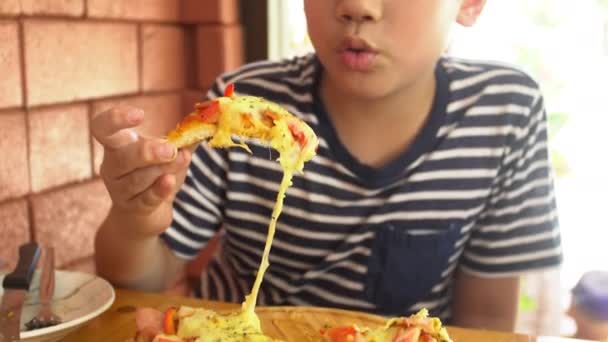Kleine asiatische Kind essen Pizza im Restaurant glücklich asiatische Junge genießen bei Ihrer Mahlzeit. — Stockvideo