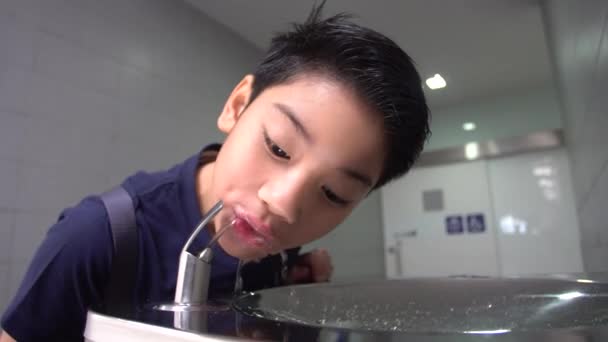 Aziatische hongerige jongen drinkwater uit water buis. — Stockvideo