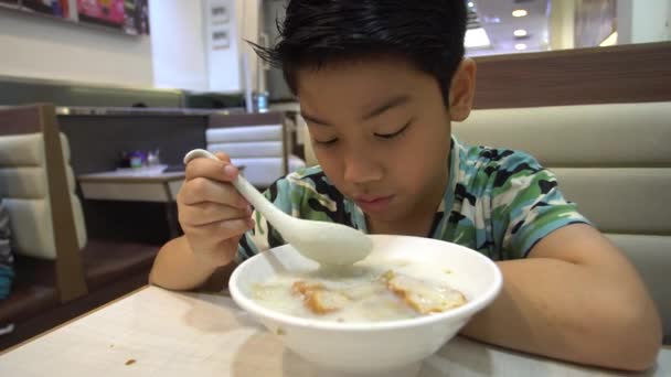 Feliz asiático preadolescentes chico disfrutar comer en mañana desayuno . — Vídeos de Stock