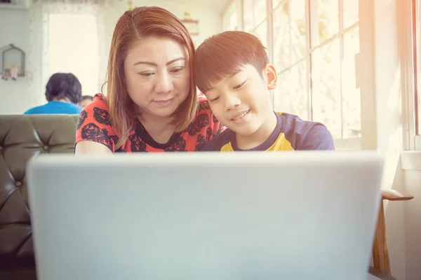 Ázsiai anya és fia ülő-on iskolapad használ a Laptop otthon — Stock Fotó