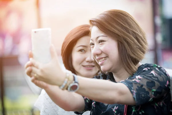 Happy asian woman with friend taking a selfie — Stock Photo, Image