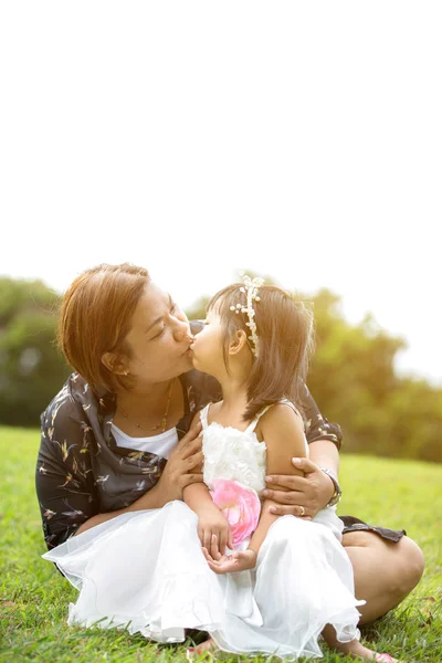 Asian mother is kissing his gaughter  in the park — Stock Photo, Image