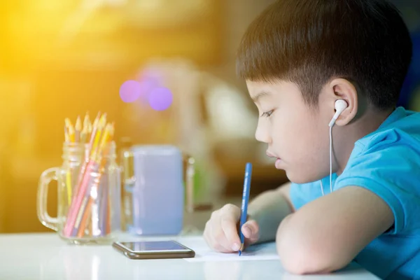 Un niño usando el celular y pintando en un papel blanco en casa —  Fotos de Stock