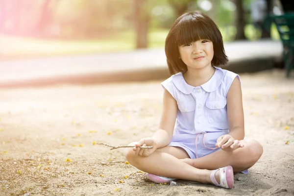 Маленький азиатский ребенок играет в песок в парке — стоковое фото