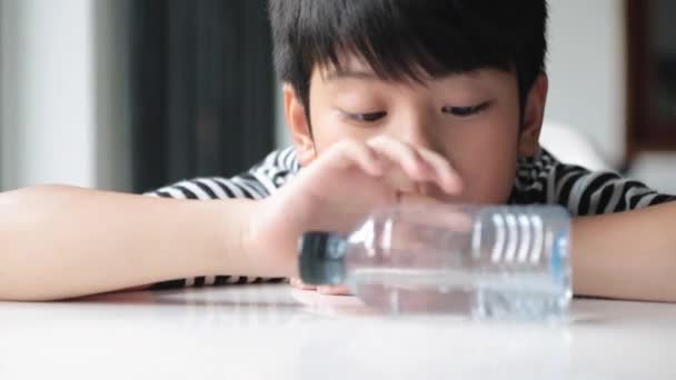 Gelukkig Aziatische schattige jongen drinkt water uit een fles . — Stockvideo