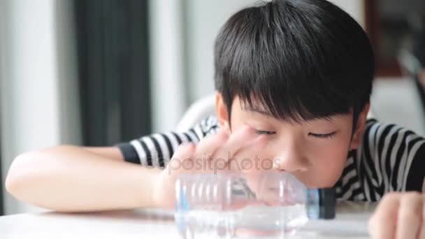 Glad asiatiska söt pojke dricker vatten ur en flaska . — Stockvideo