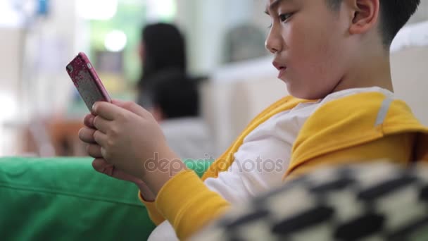 Niño asiático feliz usando un celular digital en casa  . — Vídeos de Stock