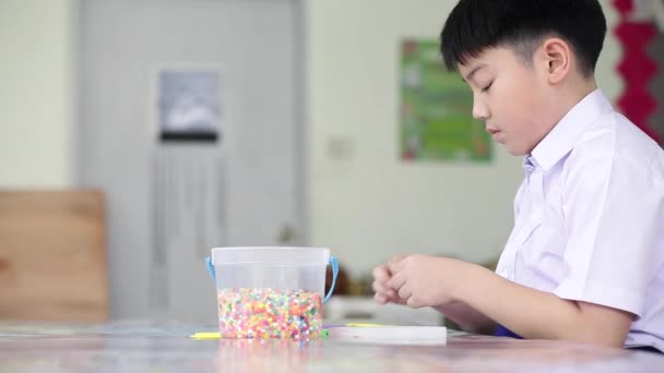 Ασιατικό χαριτωμένο αγόρι με πλαστικά παιχνίδια παιχνιδιού στο σχολείο τέχνης ώρες. — Αρχείο Βίντεο