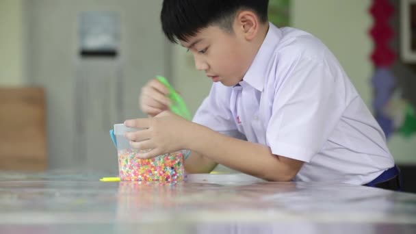 Asiático lindo chico con jugar juguetes de plástico en la escuela, horas de arte . — Vídeos de Stock