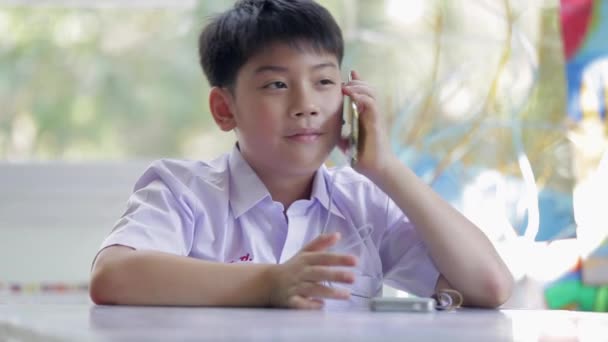 Gelukkig Aziatische kind met behulp van een mobiele telefoon belt met moeder . — Stockvideo
