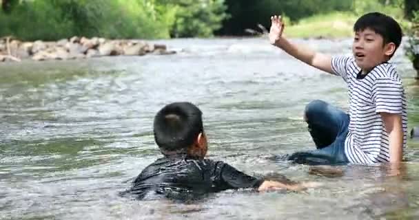 Glücklich zwei asiatische junge spielen Wasserfall in Thailand — Stockvideo