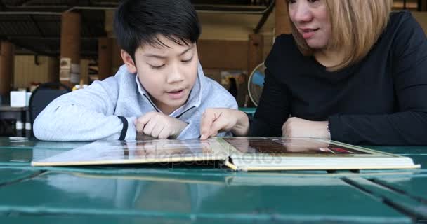 Asian söt pojke med mamma läsa menyn bok och punkt. Glada ansikte — Stockvideo