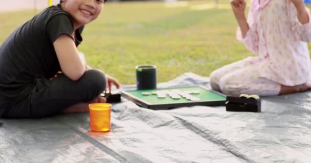 Happy asian boy and girl playing board game in camping area — Stock Video