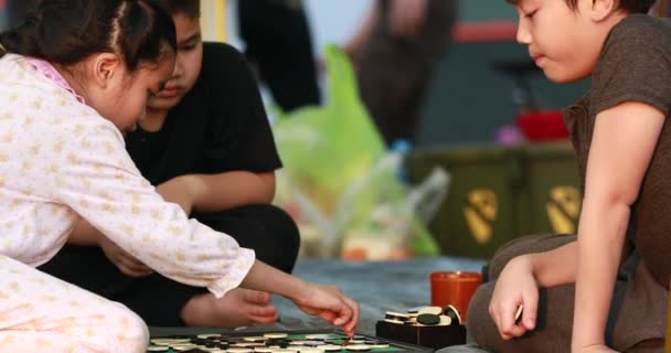 Gelukkig Aziatische jongen en meisje spelen bordspel op camping gebied — Stockvideo
