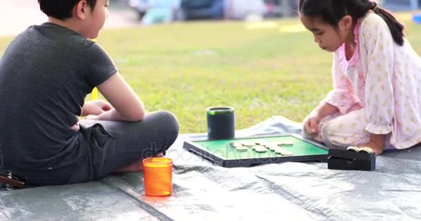 Feliz asiático menino e menina jogar jogo de tabuleiro na área de acampamento — Vídeo de Stock