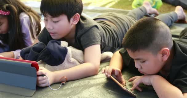 Feliz ásia menino e menina jogar inteligente telefone e tablet no camping área — Vídeo de Stock