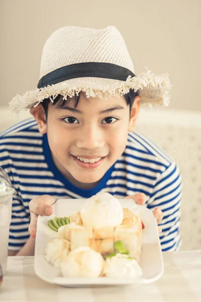 甘い食べ物を楽しんでいるかわいいアジアの少年. — ストック写真