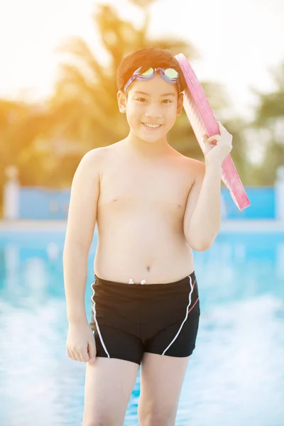 Lykkelig asiatisk gutt i badedrakt kommer opp i bassenget – stockfoto