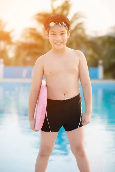 Lykkelig asiatisk gutt i badedrakt kommer opp i bassenget – stockfoto