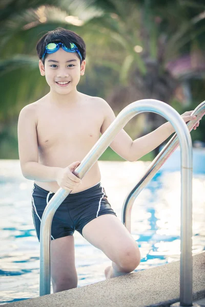 Lykkelig asiatisk gutt i badedrakt kommer opp i bassenget – stockfoto