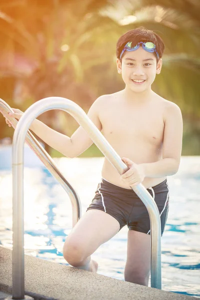 Lykkelig asiatisk gutt i badedrakt kommer opp i bassenget – stockfoto