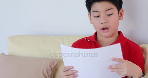 Asiático joven chico leyendo un papel hoja — Vídeo de stock