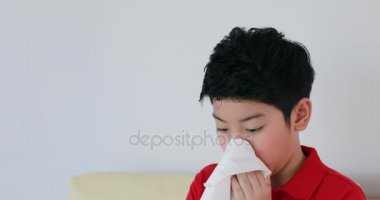 Genç Asyalı çocuk tuvalet kağıdı kullanarak burnunu darbeler