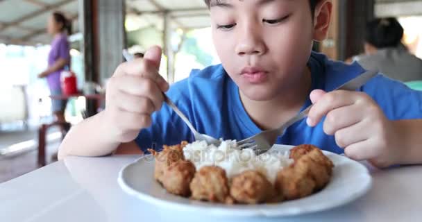 Mały chłopiec azjatyckich jeść smażony ryż z mięsem piłkę. — Wideo stockowe