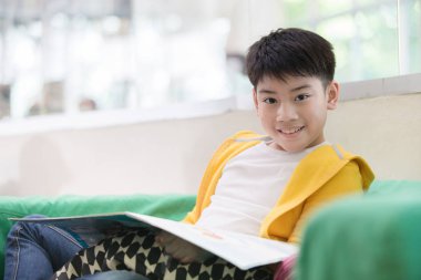 Mutlu Asyalı çocuk gülümsemek yüz kitap okuma.