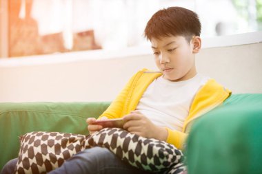 Asyalı çocuk gülümsemek yüz ile cep telefonu kullanarak .