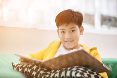 Mutlu Asyalı çocuk gülümsemek yüz kitap okuma.