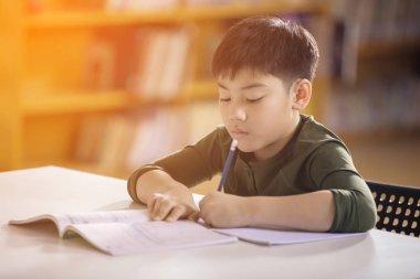 Mutlu Asyalı çocuk gülümsemek yüz ile ödev. 