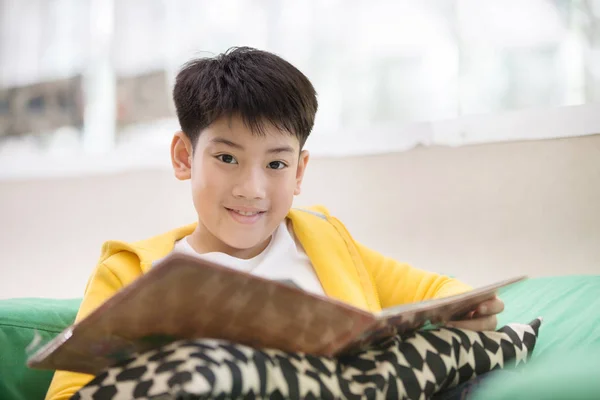 Šťastné Asijské dítě čtení knihy s tváří úsměv. — Stock fotografie