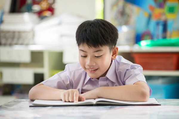 Felice asiatico bambino lettura libro con sorriso faccia . — Foto Stock