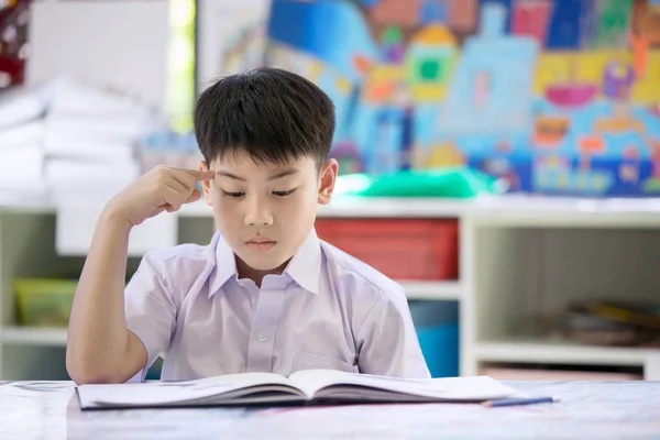 Feliz asiático niño reafeliz asiático niño leyendo libro y pensando —  Fotos de Stock