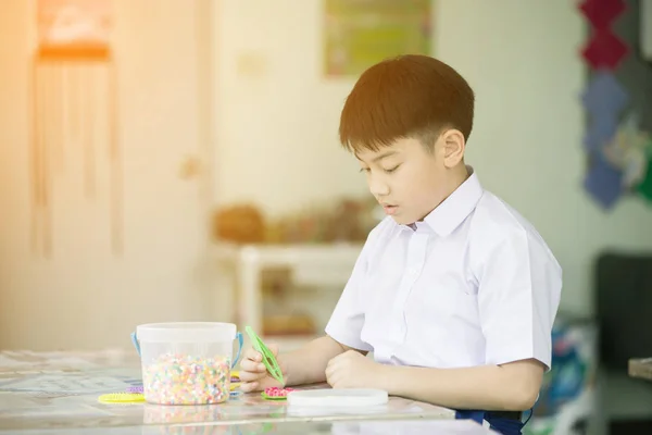 Asijské dítě při pohledu na své řemeslo ve školce — Stock fotografie