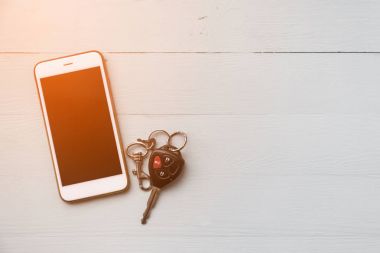 Ahşap arka planda cep telefonu ve uzaktan kumandalı araba anahtarları