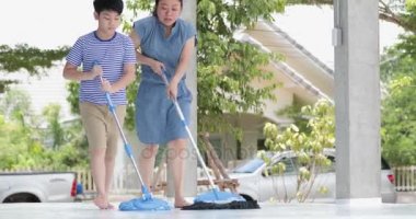 Mutlu Asya ailesi odayı temizler. Anne ve oğlu evde temizlik yapmak. Genç bir kadın ve bir küçük çocuk çocuk toz sildi ve yere vakum.