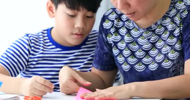 Asyalı çocuk anne ile kağıt katlama sanatı Japon kağıt origami katlama için öğrenme. — Stok video