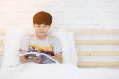 Mutlu Asyalı çocuk yatağa hikaye kitabı okuma