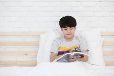 Mutlu Asyalı çocuk yatağa hikaye kitabı okuma
