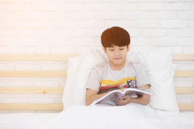 Mutlu Asyalı çocuk yatağa hikaye kitabı okuma