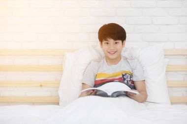 Mutlu Asyalı çocuk yatağa hikaye kitabı okuma