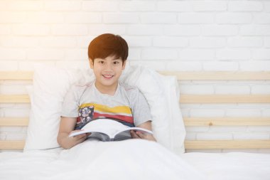 Mutlu Asyalı çocuk yatağa hikaye kitabı okuma