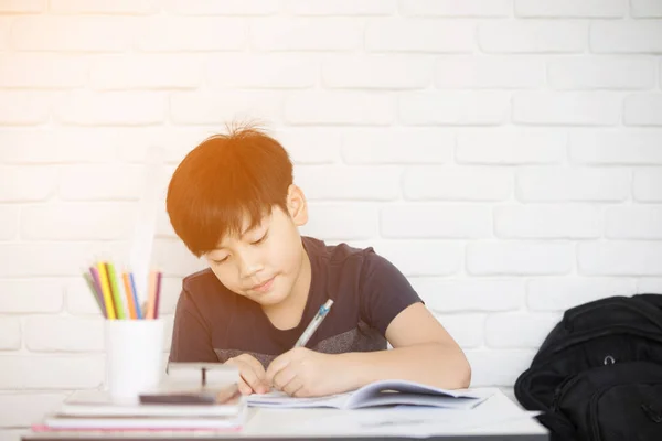 Asiatische junge Hausaufgaben in der Nähe von weißen Ziegelwand — Stockfoto