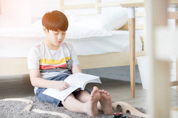 Ευτυχισμένος Ασίας αγόρι διαβάζοντας ιστορία βιβλίο κοντά στο λευκό κρεβάτι — Φωτογραφία Αρχείου