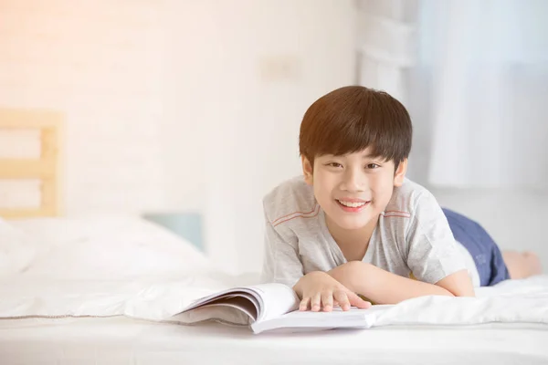 Ευτυχισμένος Ασίας αγόρι διαβάζοντας ιστορία βιβλίο στο κρεβάτι — Φωτογραφία Αρχείου