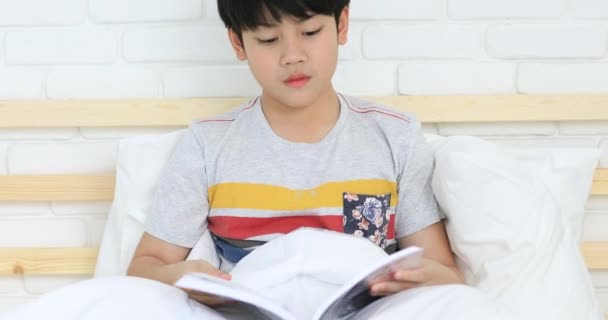 Ασιατικό χαριτωμένο αγόρι, διαβάζοντας ένα βιβλίο πριν από την τελική δοκιμή στο σπίτι . — Αρχείο Βίντεο